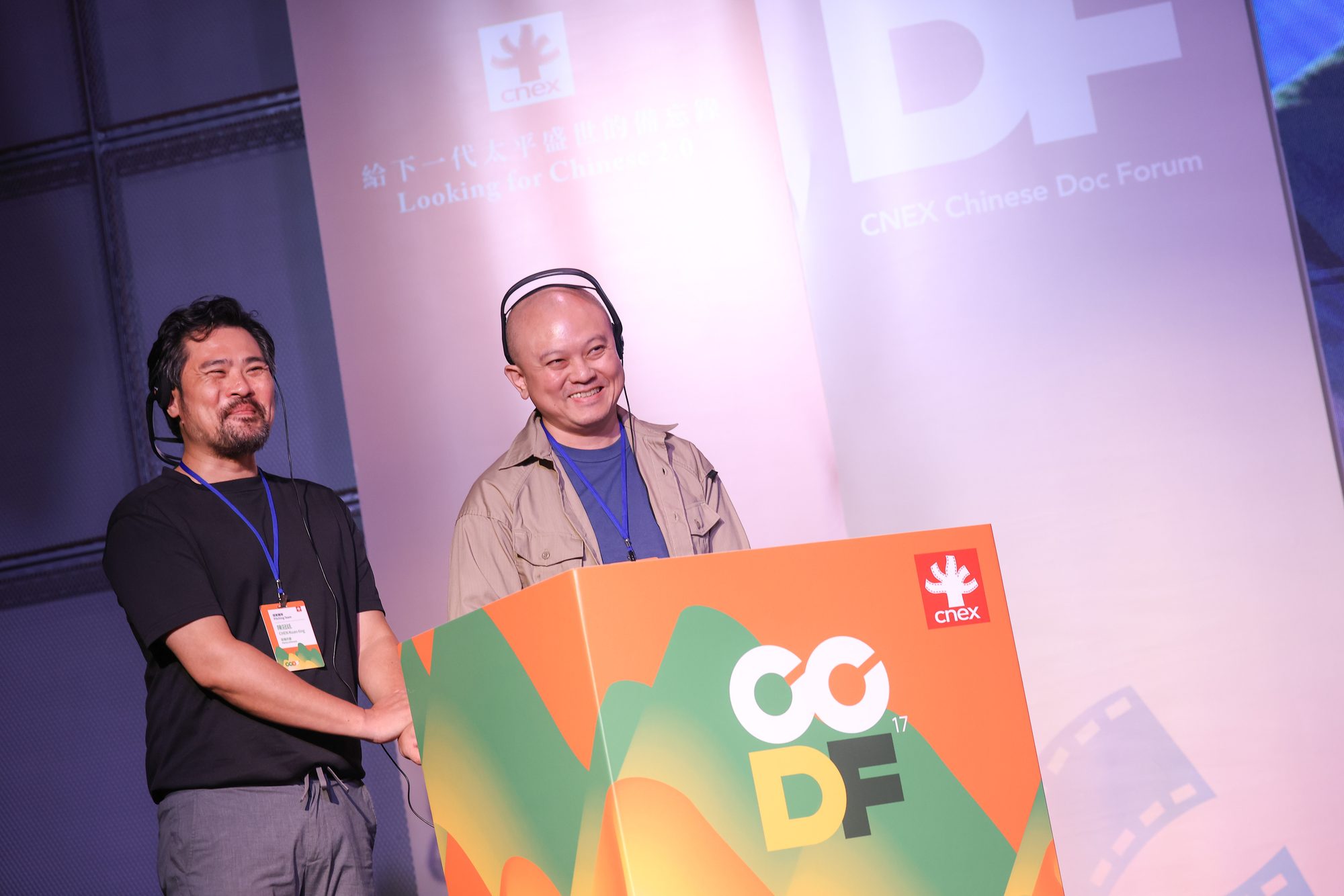 製片陳冠廷與導演張晃維戴著同步口譯耳機，於 CCDF-17 提案台前面帶笑容回應評審